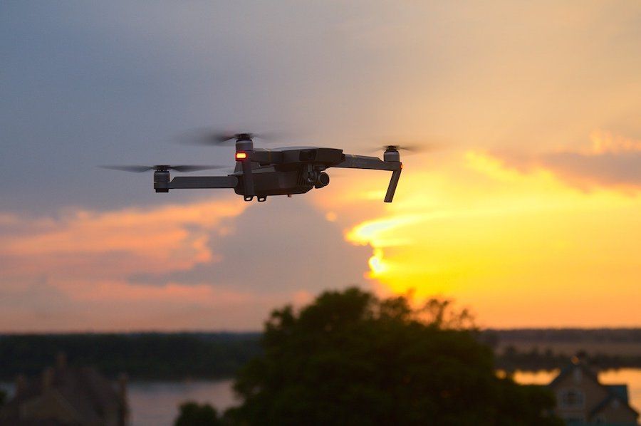 Létající dron na obloze při západu slunce