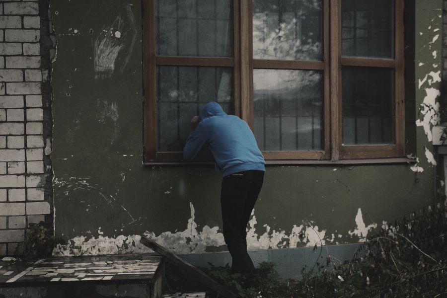 Muž kouká do domu skrz okno