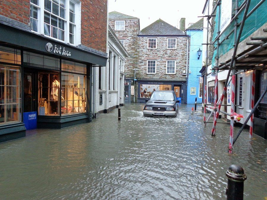 Zaplavená ulice s obchody a autem