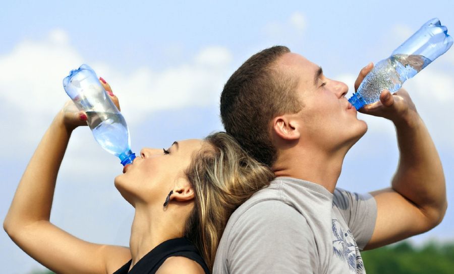 Muž a žena pijí vodu z láhve